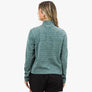 Back view of a person wearing a light teal long sleeve with black shorts against a white background.