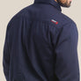 Back view of a man wearing a navy blue shirt with Ariat logo on the back shoulder against a an background