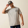 Man wearing a gray t-shirt with a logo and a cap on a beige background