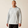 Man wearing a light gray hoodie with 'Ariat' branding on a beige background