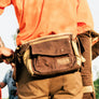 A person wearing a waist bag with an orange shirt and khaki pants.