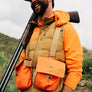 Person wearing an orange strap vest in a field.