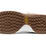 Bottom view of a shoe sole that is brown and white with a yellow Keen logo in the middle off to the side.