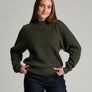 Person in a dark green sweater against a grey background.