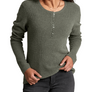 Person wearing a dark green sweater with buttons going a 1/4 of the way down the front, they are also wearing grey pants against a white background.