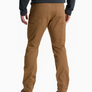 Back view of a person wearing a pair of tan pants with a dark grey shirt and brown shoes against a white background.