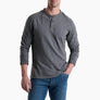 Person wearing a long sleeve grey shirt with 3 buttons and blue jeans against a white background.