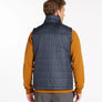 Back view of a person wearing a navy blue vest with an orange long sleeve shirt against a white background.