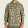 Person wearing a camo hoodie with a Marshwear tag on the large pocket.