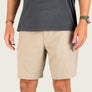 Person wearing beige shorts and a dark shirt on a plain background