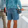 Person fishing on a boat wearing blue shorts