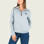 Woman wearing a light blue pullover with a small logo on a white background