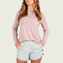 Woman wearing a light pink long-sleeve top and light gray shorts on a white background