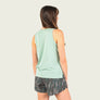 Woman wearing a light green sleeveless top and patterned shorts on a plain background