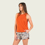 Person wearing a burnt orange tank top with camo shorts against a blank background