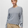A person wearing a light grey sweater with khaki pants against a white background.