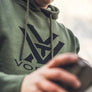 Person wearing a green sweatshirt with a Vortex logo in black on the front.