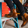 Person going up a ladder wearing a pair of brown boots.