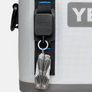 Up-close image of a Yeti retractable clip attached to another Yeti product with a pocket knife clipped to it.