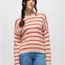 Person wearing a cream and orange striped sweater with blue jeans against a grey background.