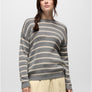 Person wearing a grey and cream colored striped sweater with a cream colored skirt against a white background.
