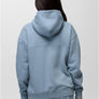 Back view of a person wearing a light blue hoody with the same colored sweatpants against a grey background.