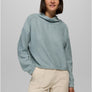 Person wearing a light blue sweatshirt with cream colored pants against a light grey background.