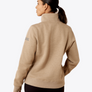 Back view of a person wearing a tan colored sweatshirt against a grey background.