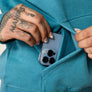 Up close image of a person putting their cell phone into the special pocket inside a the large pocket of a swearshirt.