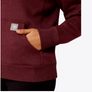 Close up image of a person putting there hand in the pocket of a maroon colored long sleeve shirt.