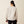 Back view of a person wearing a cream color sweatshirt and black pants against a beige background.