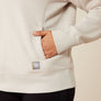 Close up view of a person putting their hand into the pocket of a shirt and have a brand tag right below the pocket.