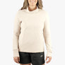 Person wearing a cream colored long sleeve with black shorts against a white background.