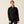 Person wearing a black jacket against a beige background.