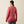 Back view of a person wearing a pink shirt that says Ariat down the sleeve of the arm against a beige background.