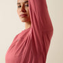 A person wearing a pink shirt with their arm raised to show the breathable fabric in the arm pit of the shirt.