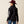 Back view of a person wearing a black jacket with white writing against a beige baackground.