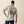 Person wearing a gray t-shirt with a skull design and text, standing against a beige background