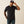 Man wearing a black t-shirt and blue jeans with a cap on a beige background