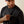 Man wearing a dark grey shirt holding out his pocket with a beige background