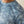 Blue camouflage-patterned shirt with 'Ariat' branding on a neutral background