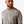 Man wearing a grey shirt with a pocket that has Ariat logo with a white background