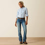 Woman wearing a light blue button-up shirt, jeans, and brown shoes on a beige background