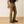 Man wearing khaki pants with tools in his cargo pocket against a light grey background and wood floor.