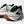White running shoes with black laces and brown heel accents on a white background
