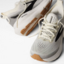 White and gray running shoes with brown soles on a white background