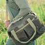 Person carrying a large bag in a field.