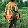 Person wearing a waist bag that has three large pouches walking in a field.