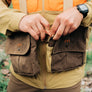 Person latching a strap vest that is brown and tan.