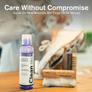 An image focused on Jason Markk shoe cleaning solution and a brush with a person blurred in the background cleaning a shoe with that cleaning product.